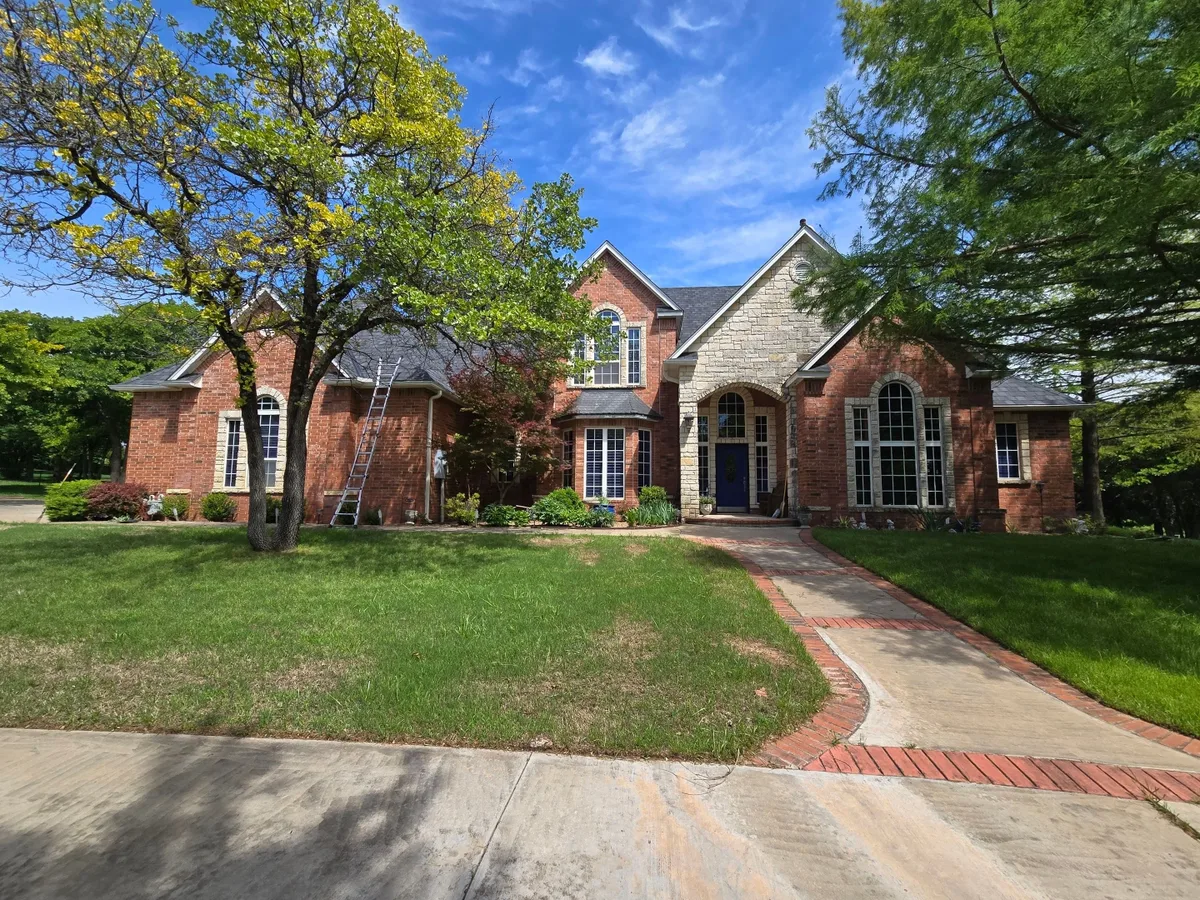 Ladder set up against a stone and brick tudor-style home for a roof inspection