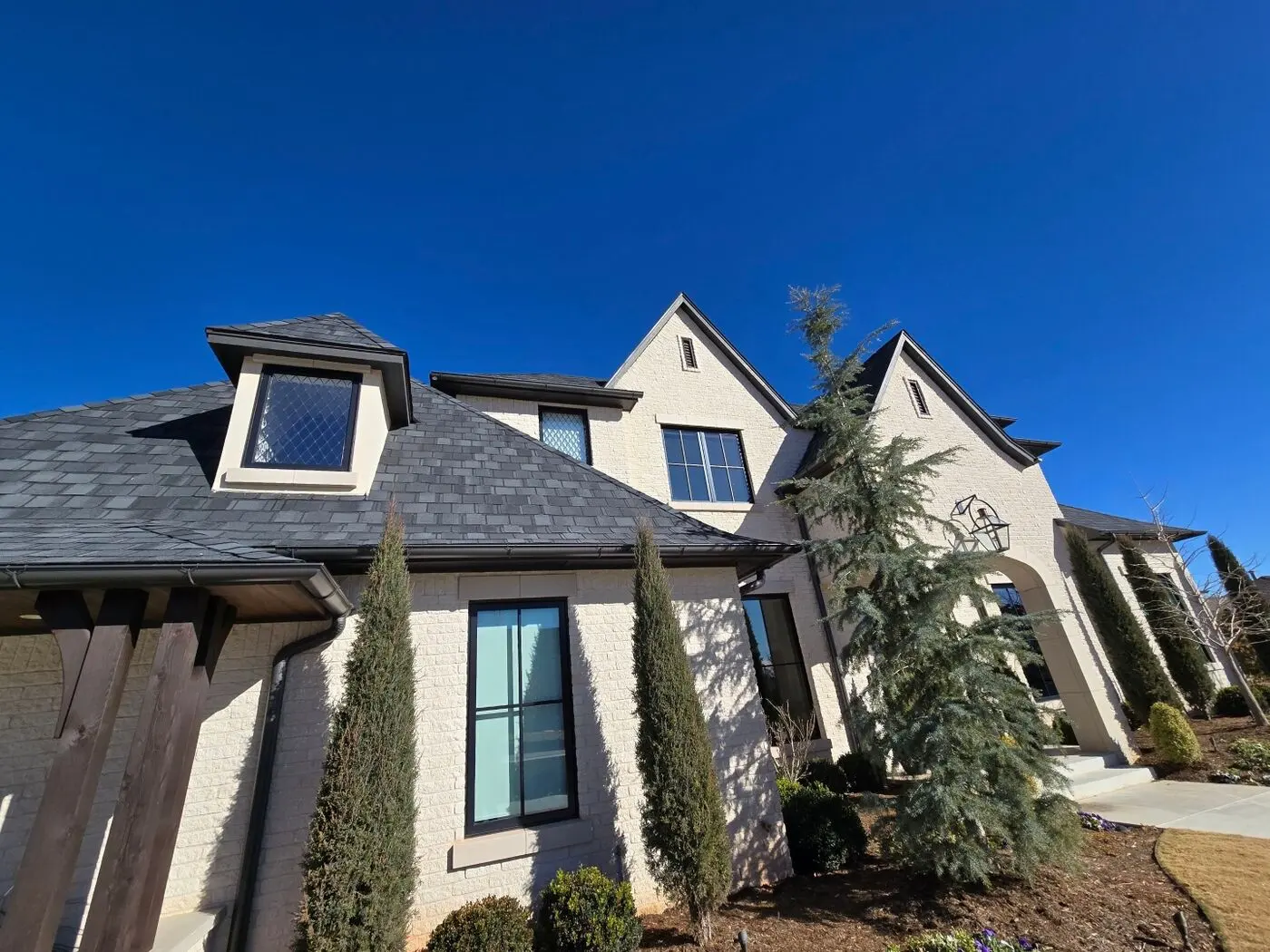 Finished slate-style shingle roof on a white brick two-story home